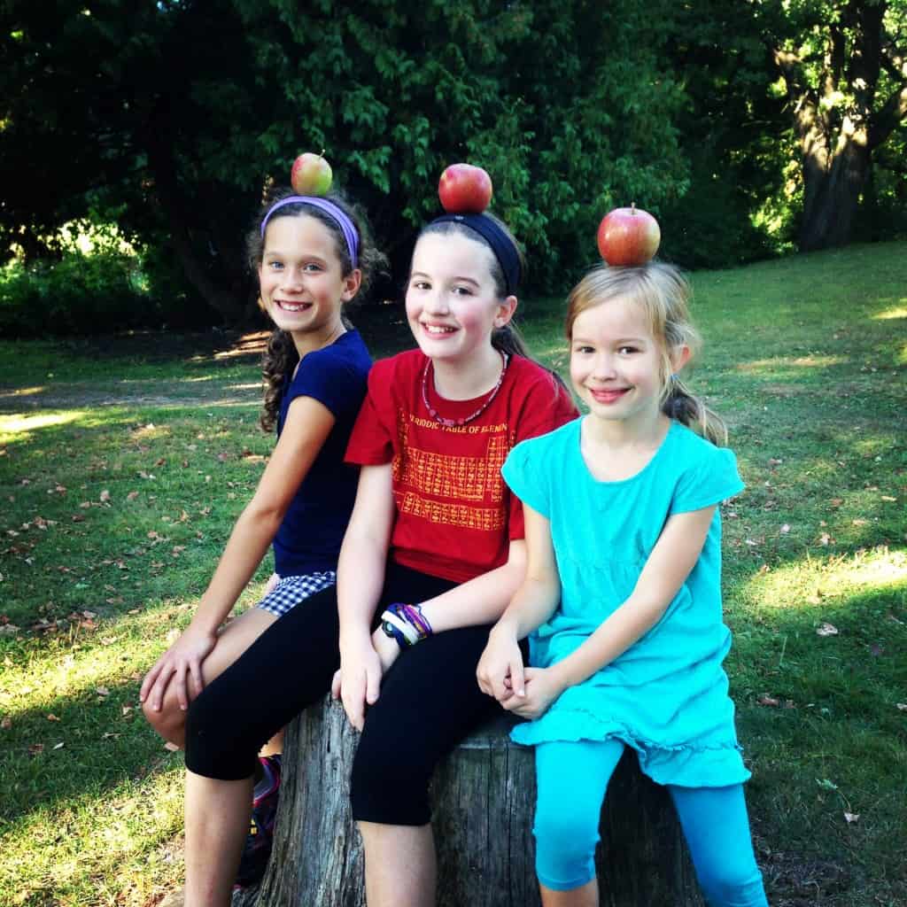 three girls posing with apples on their heads