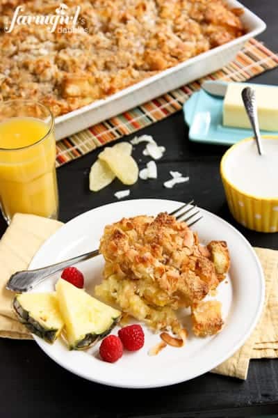 Coconut-Ginger Baked French Toast on a white plate with fresh pineapple and raspberries