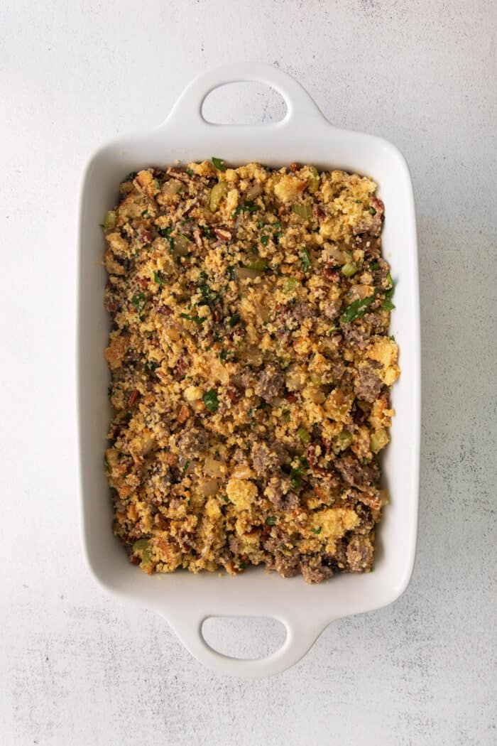 Overhead view of cornbread dressing with sausage in a white casserole dish