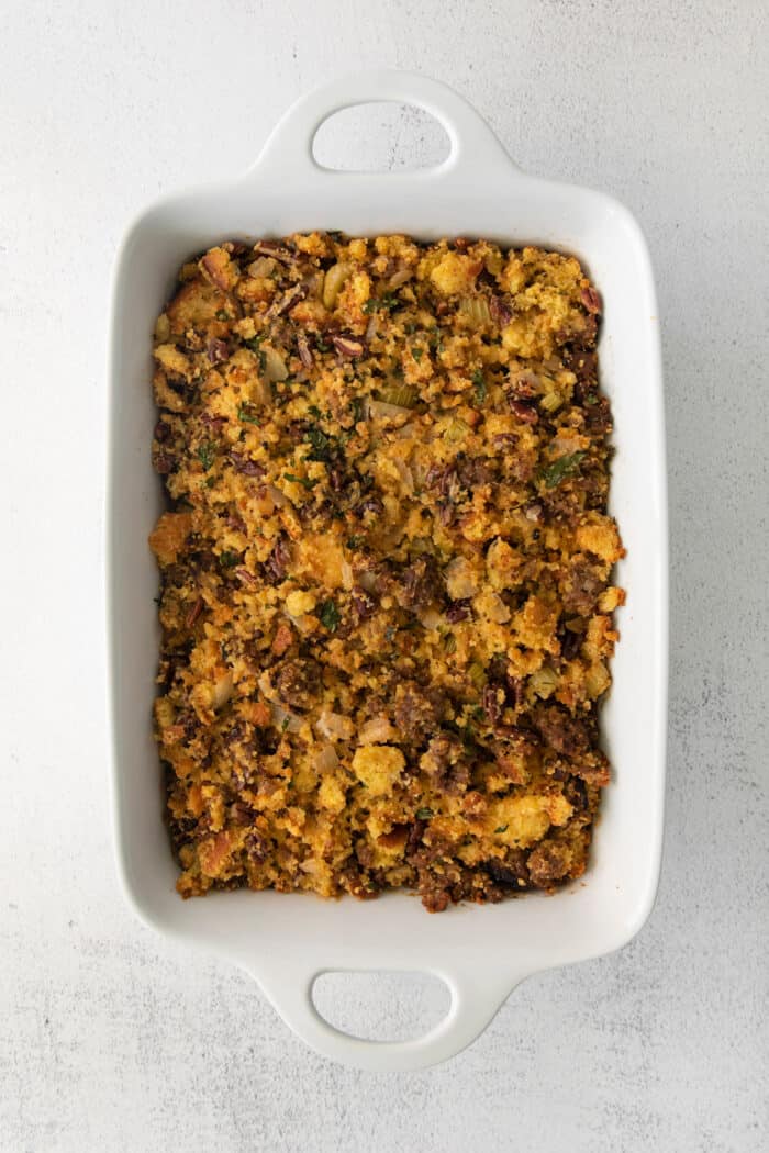 Overhead view of cornbread dressing with pecans in a white casserole