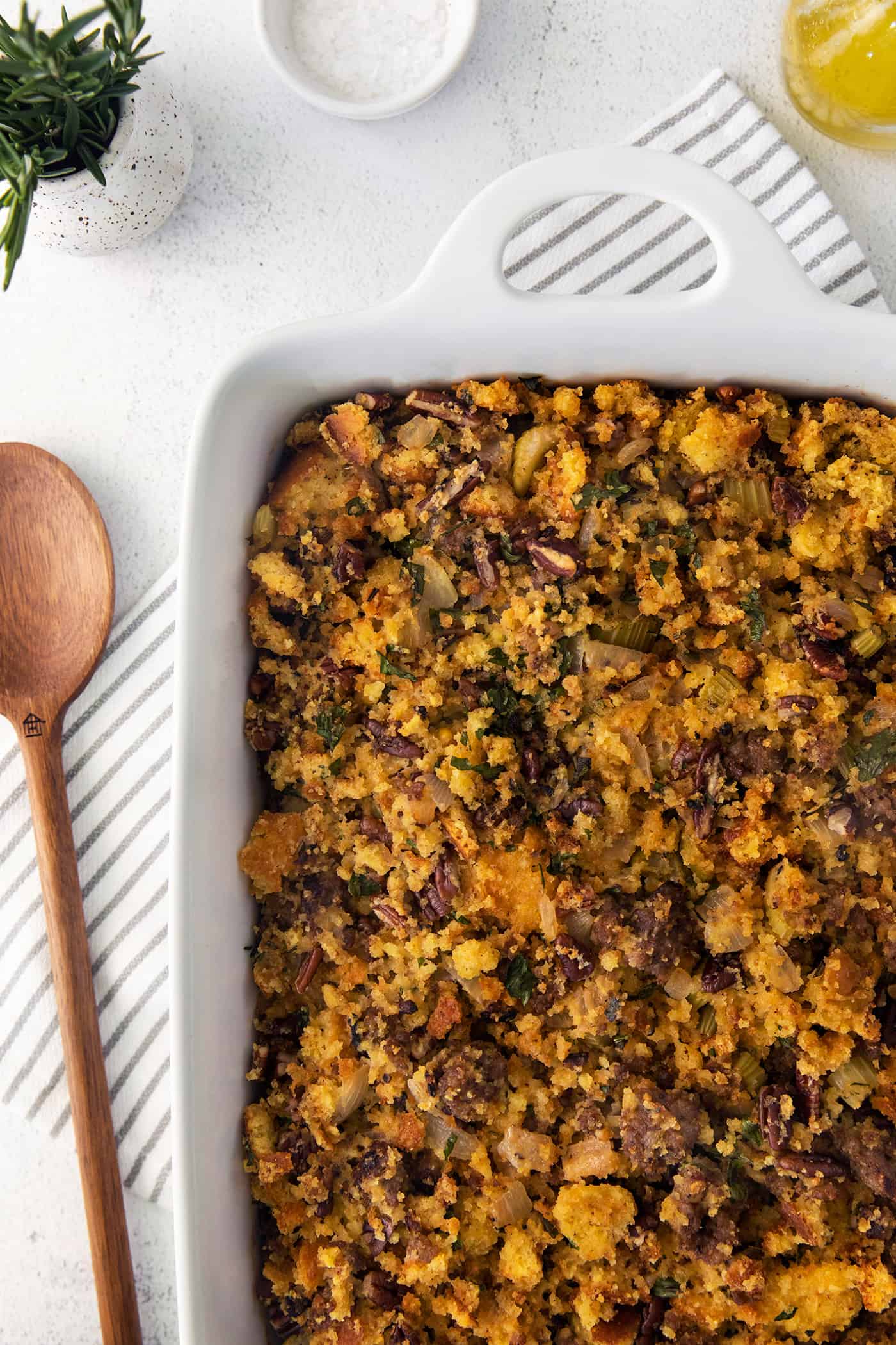 Cornbread dressing in a casserole dish with a wooden spoon next to it