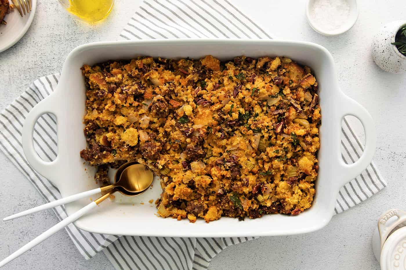 A white casserole dish of cornbread dressing with a serving mising