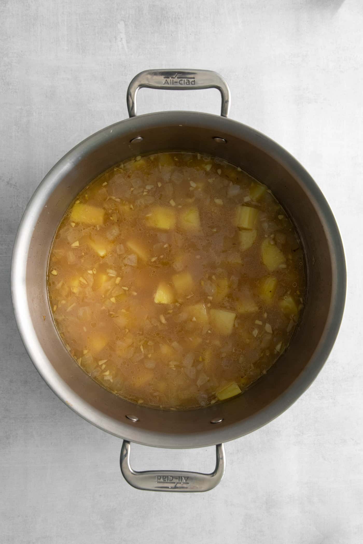 Diced potato in chicken broth in a pot