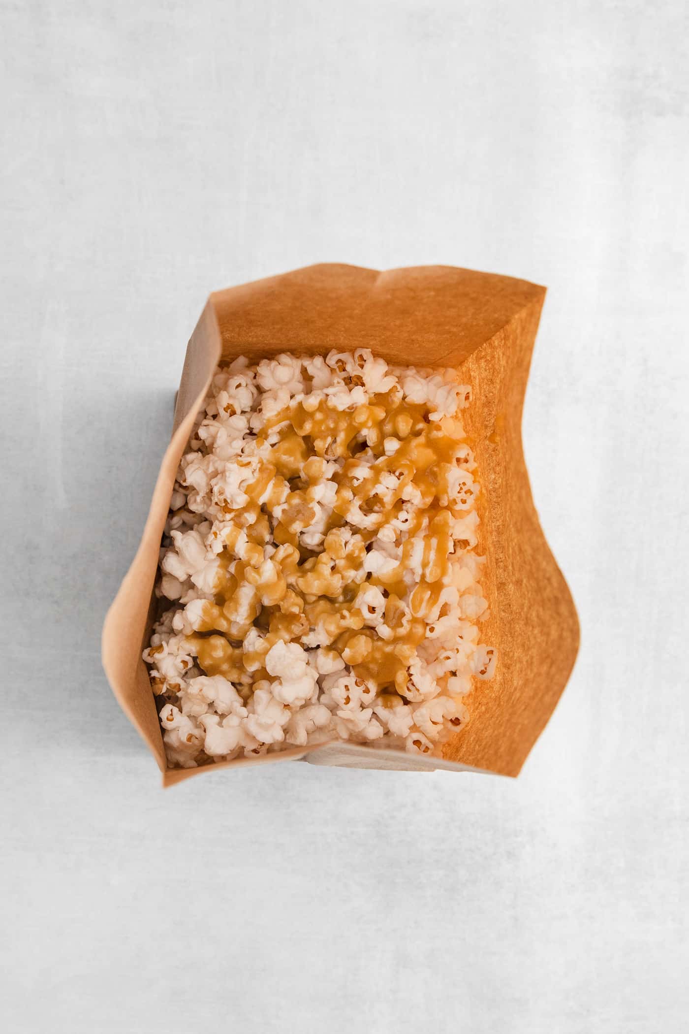 Caramel drizzled over popcorn in a paper bag