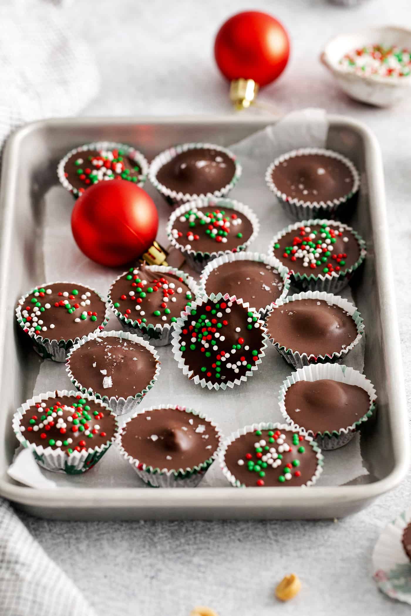 Peanut butter cups with Christmas sprinkles on a baking sheet