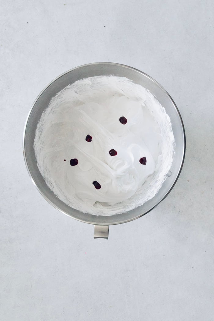 Food coloring added to marshmallow mixture in mixing bowl.