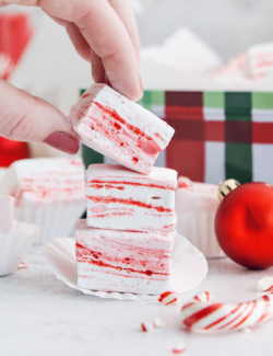 Hand lifting peppermint marshmallow from stack.