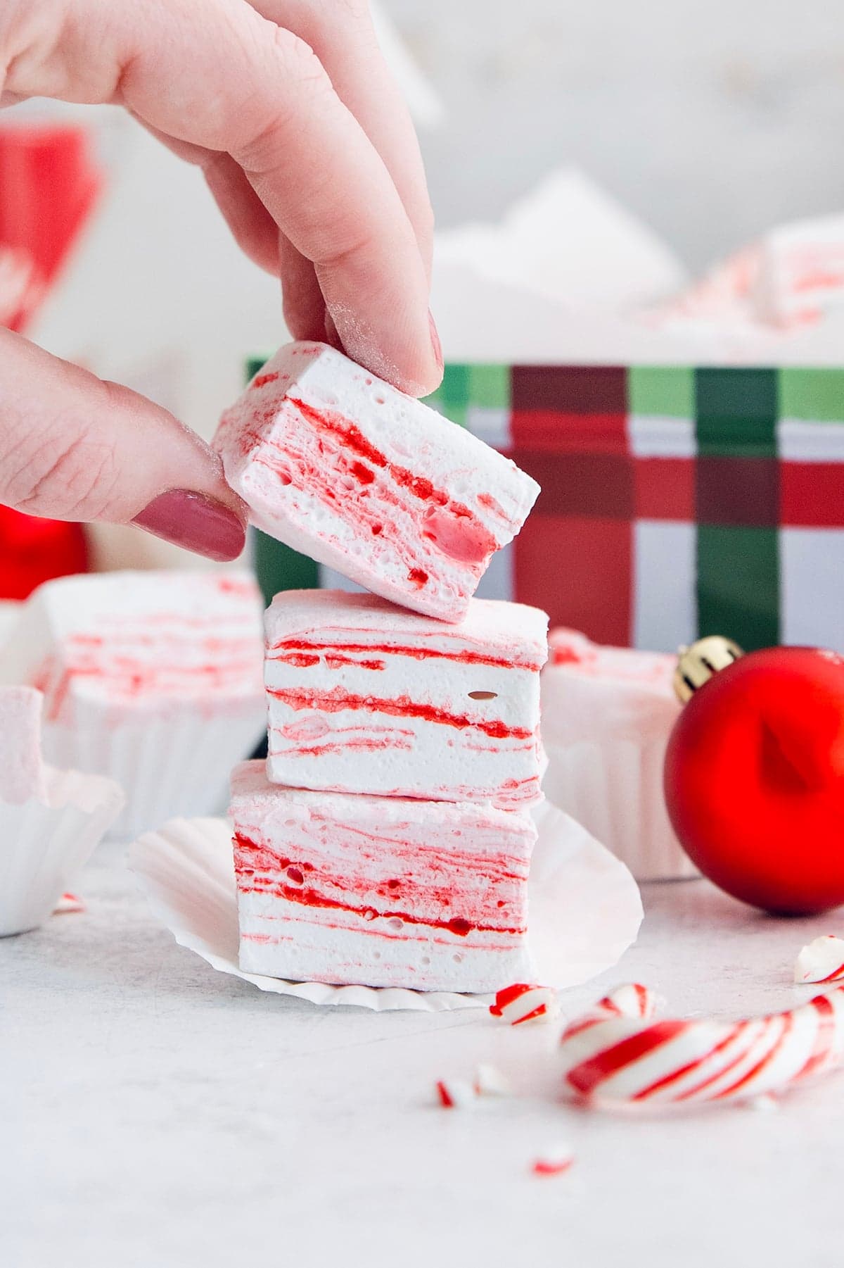 Hand lifting peppermint marshmallow from stack.