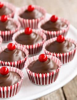 Striped baking cups filled with chocolate and topped with a red round candy