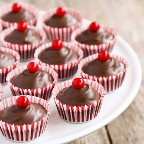 Striped baking cups filled with chocolate and topped with a red round candy