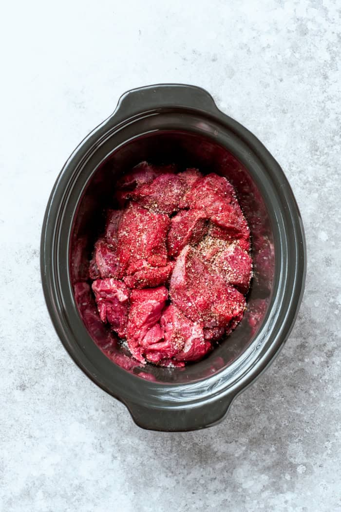 Overhead view of seasoned beef in crockpot
