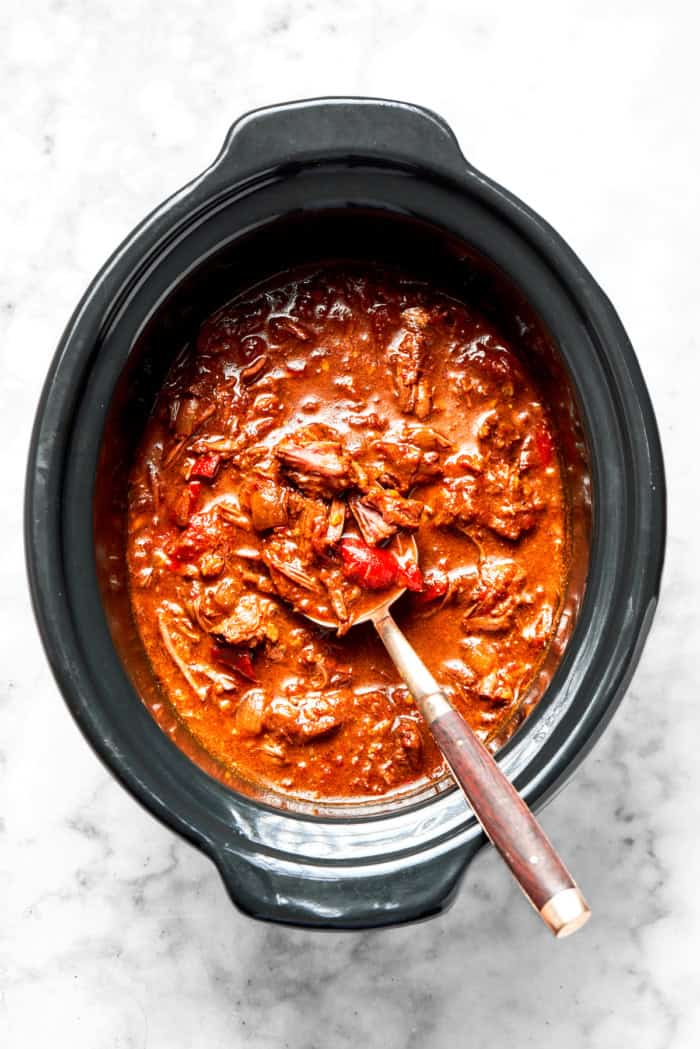 Overhead view of slow cooker beef curry in crockpot with spoon