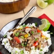 a black bowl of rice and topped with Coconut Curry Beef