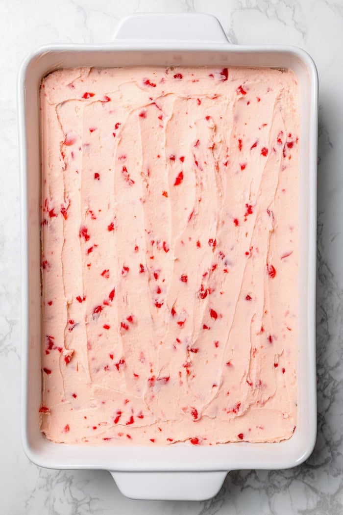 Cherry buttercream spread onto pan of brownies.