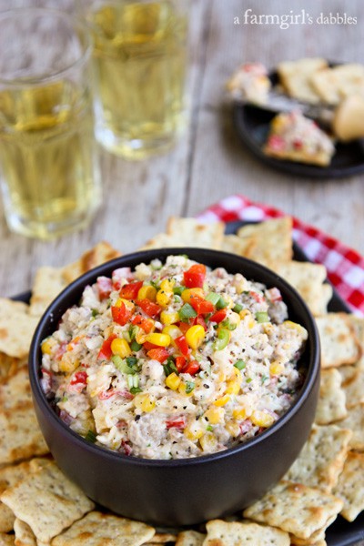 a bowl of Cheesy Corn and Sausage Dip with a plate of crackers
