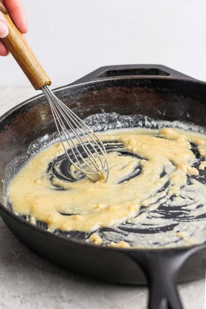 This homemade stovetop macaroni and cheese recipe is perfect for a weeknight! Ultra creamy, rich, and much quicker than the baked version. Whisking butter and flour in cast iron skillet.