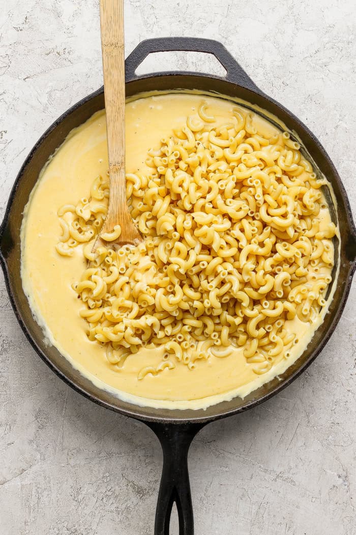 This homemade stovetop macaroni and cheese recipe is perfect for a weeknight! Ultra creamy, rich, and much quicker than the baked version. Stirring elbow noodles into cheese sauce for macaroni and cheese.