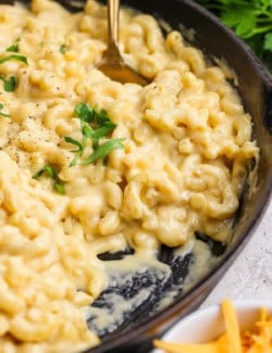 Spoon in pan of homemade macaroni and cheese.