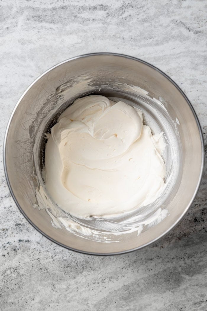 Overhead view of whipped vanilla cream frosting in mixing bowl