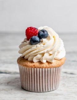 Angel food cupcake topped with whipped vanilla cream, blueberries, and raspberry