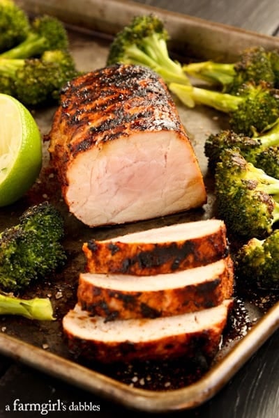 Pork Tenderloin on a rimmed pan with broccoli and fresh lime