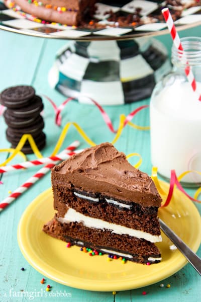 a frosted chocolate layer cake with oreos on a yellow plate