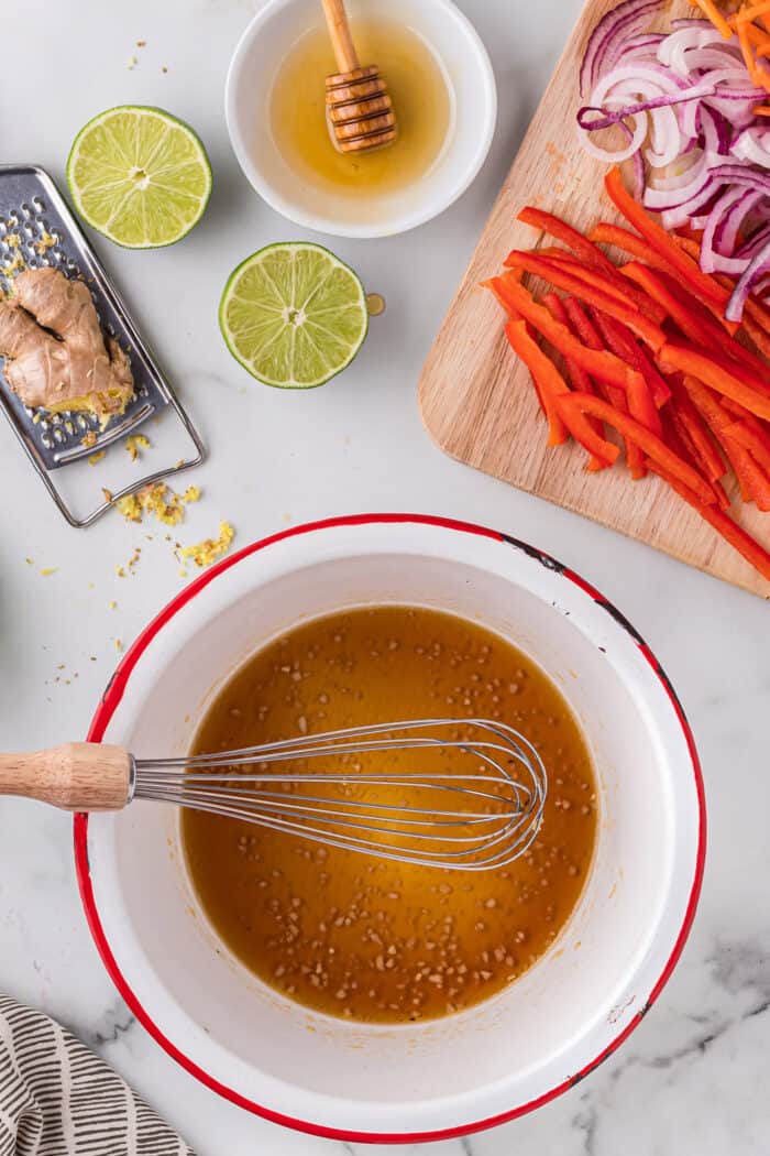 A whisk stirring Asian slaw vinaigrette