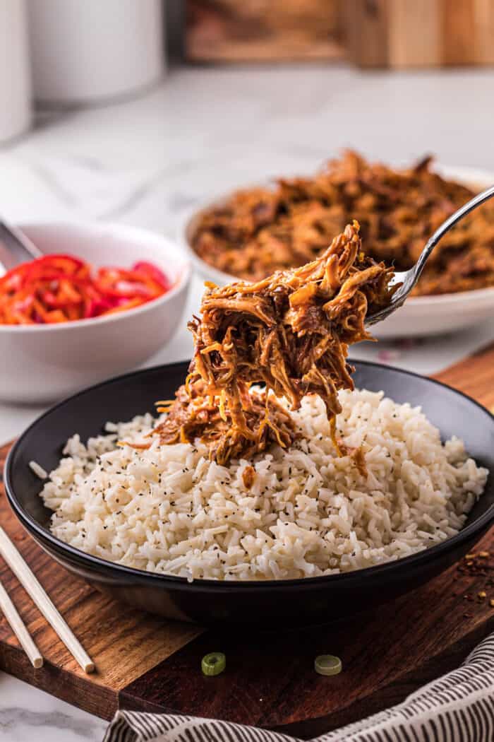 Shredded orange chicken being added to white rice