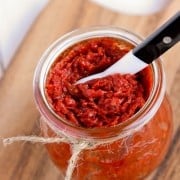 a jar of Sun-Dried Tomato Spread with a black and white serving spoon