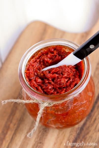 a jar of Sun-Dried Tomato Spread with a black and white serving spoon