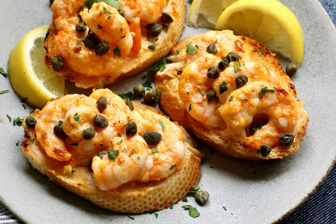 Three sriracha shrimp toasts on a gray plate.