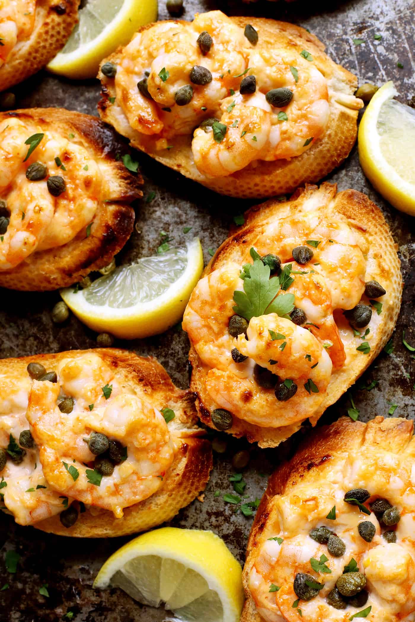 Sriracha garlic shrimp toast is made with tender shrimp, spicy sriracha mayo, and lightly crispy toast! An easy appetizer or light meal. Overhead view of sriracha garlic toast with shrimp on a gray plate.