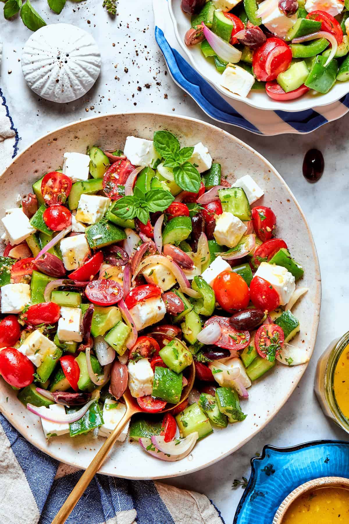 This Greek Chopped Salad is loaded with fresh cucumbers, tomatoes, bell peppers, and herbs and drizzled with a bright, flavorful dressing. Overhead view of chopped greek Salad in bowl with spoon