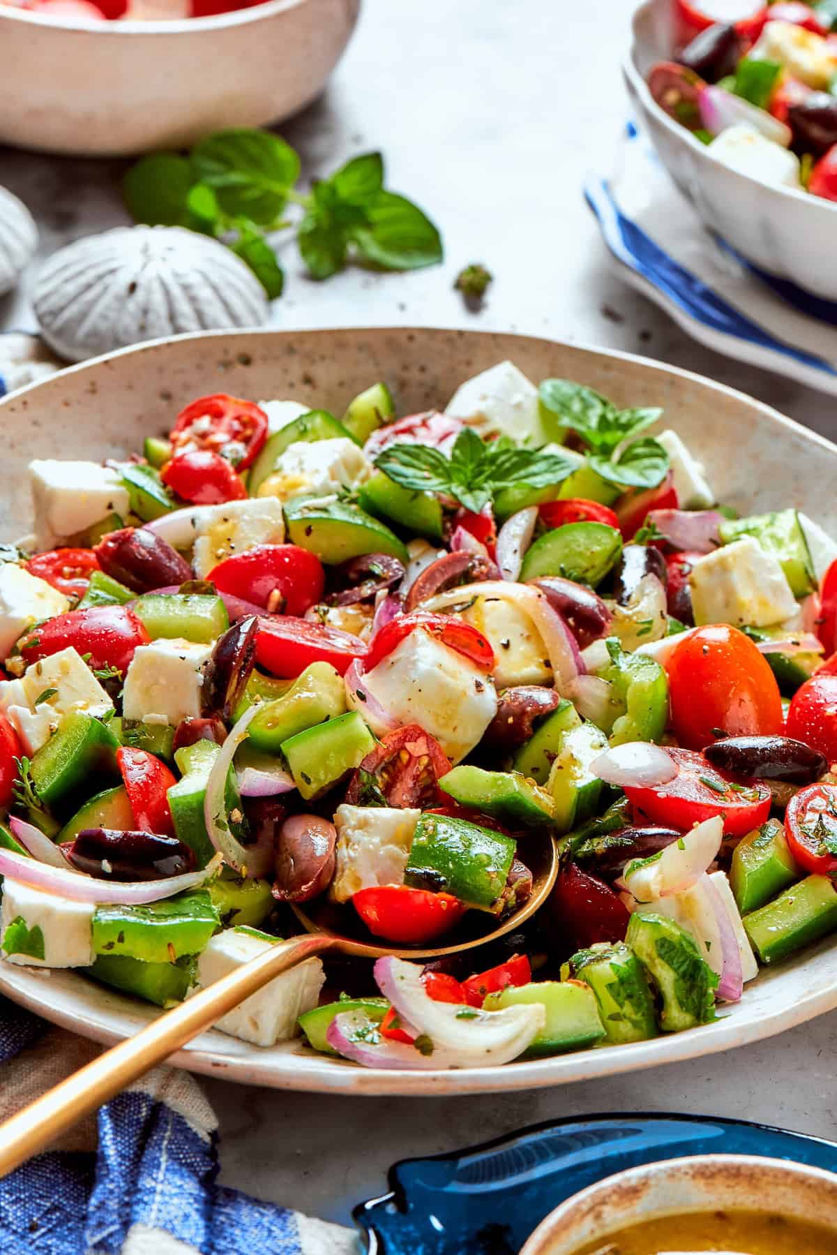This Greek Chopped Salad is loaded with fresh cucumbers, tomatoes, bell peppers, and herbs and drizzled with a bright, flavorful dressing. Bowl of chopped Greek salad with spoon
