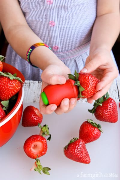 a young girl hulling strawberries