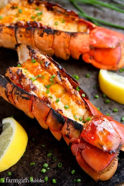 Lobster Tails topped with Sriracha Butter, green onions, and lemon slices