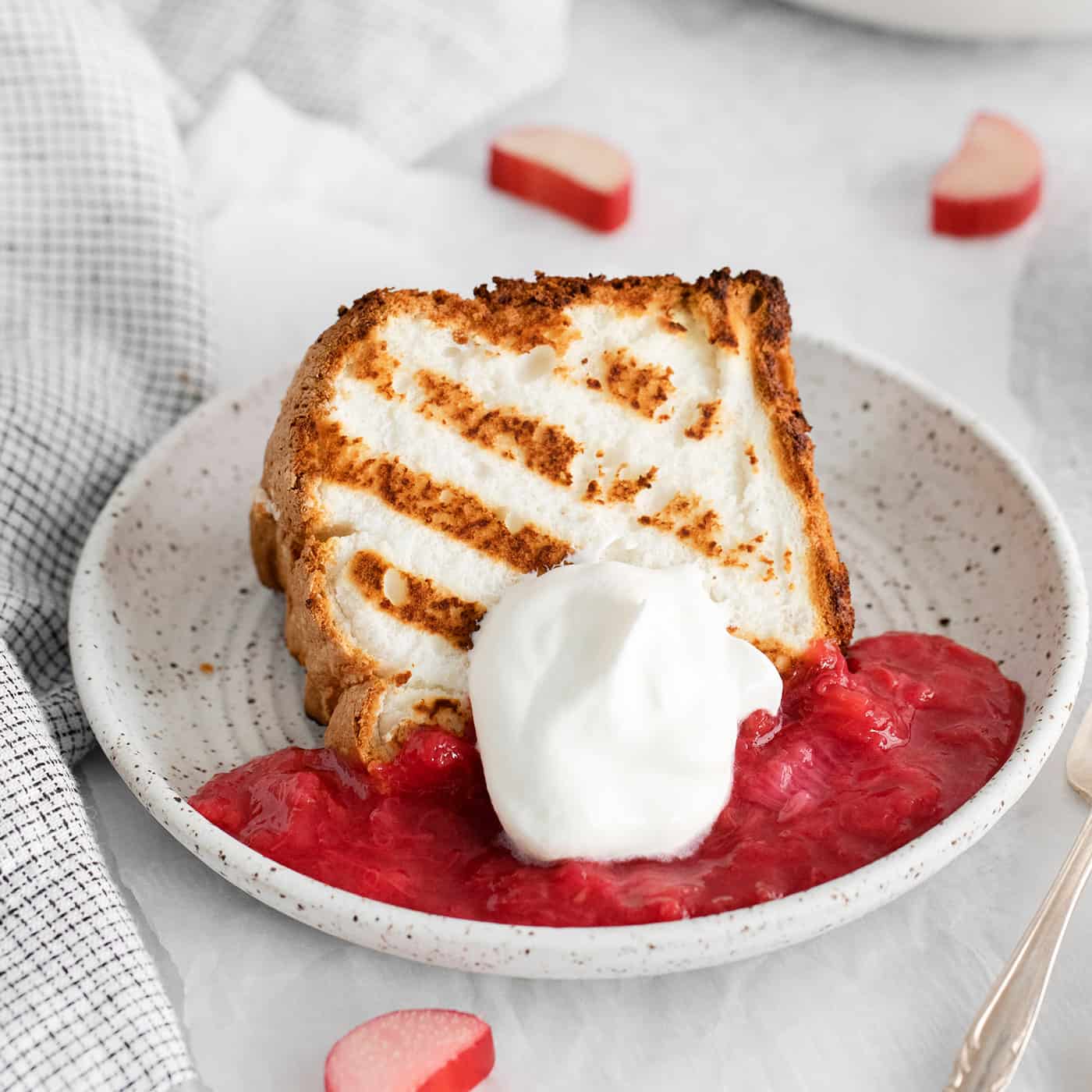 A slice of grilled angel food cake with rhubarb sauce on a plate