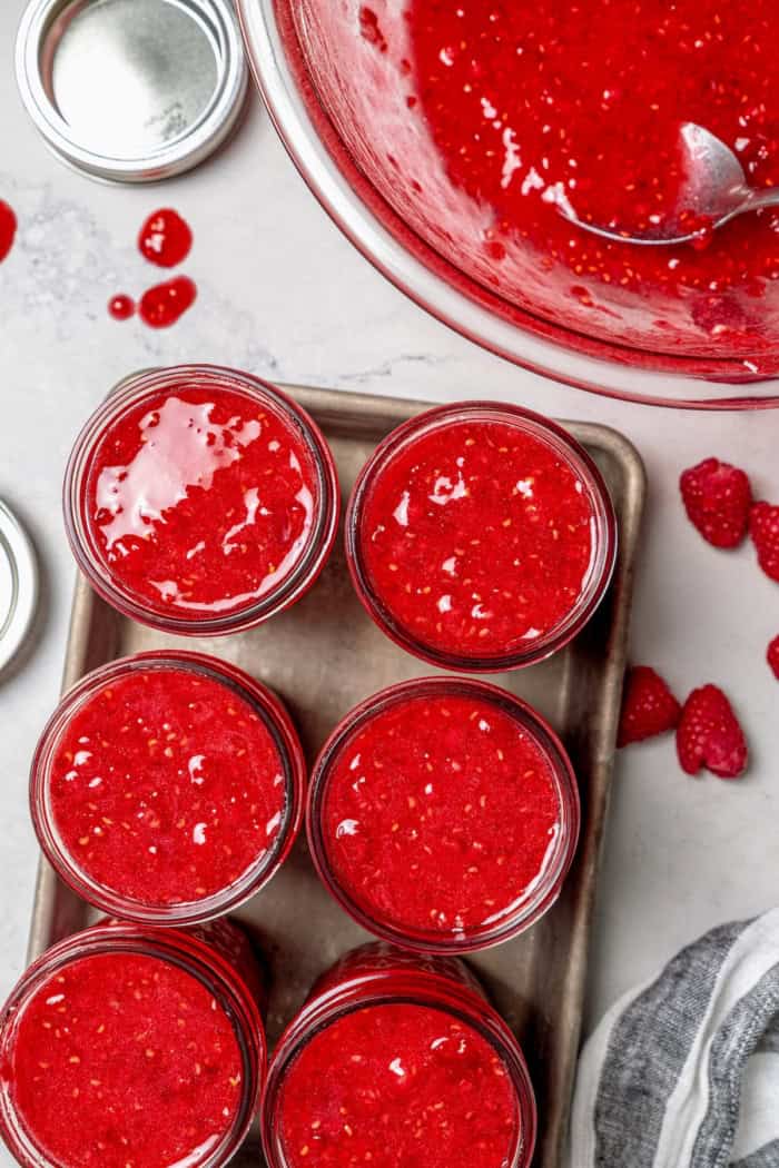 Overhead view of 6 jars filled with raspberry freezer jam