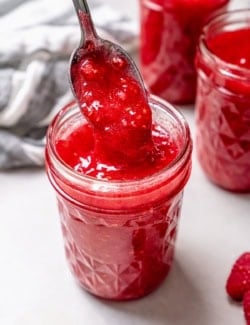 Spoonful of raspberry freezer jam held over jar