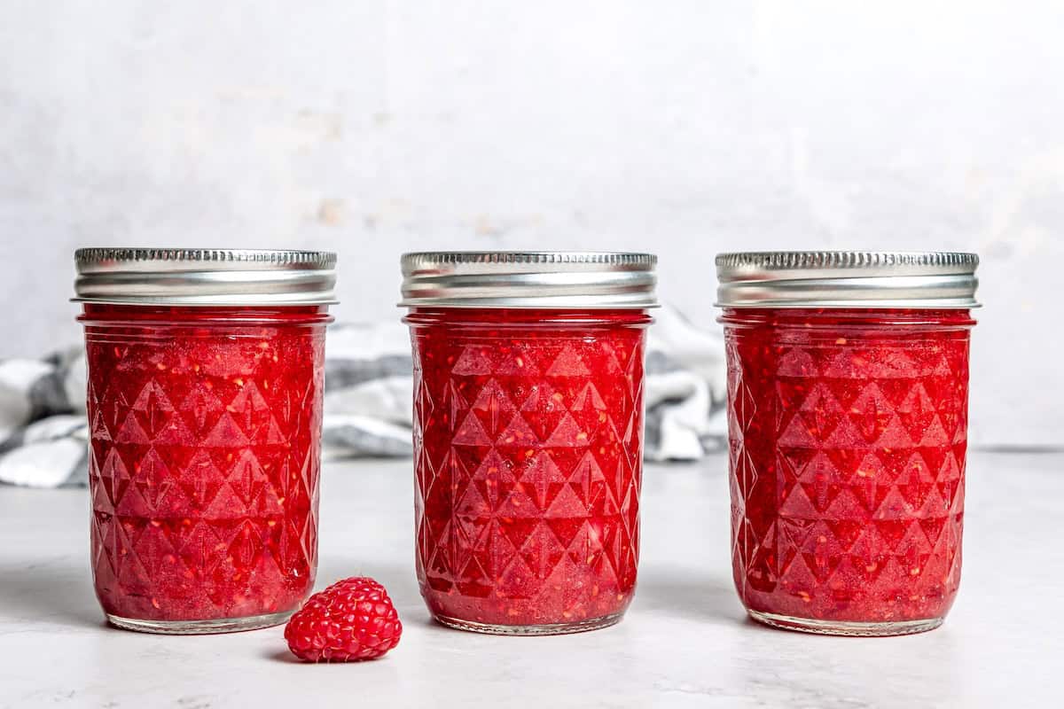 3 jars of raspberry freezer jam on countertop