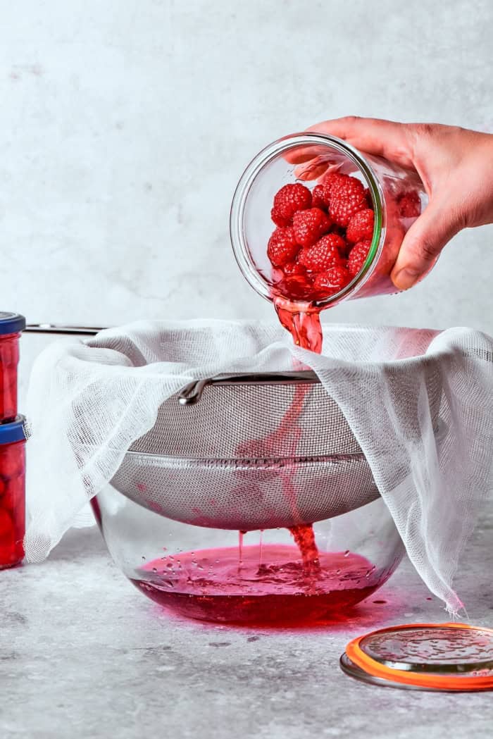 Made with just 3 simple ingredients, this homemade raspberry vinegar recipe is incredibly easy and fantastic for dressings, drinks and more! Pouring raspberry vinegar through cheesecloth.