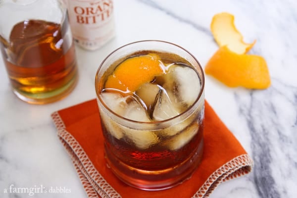 A Glass of Old Fashioned Bacon Bourbon on the Rocks Next to an Orange Peel