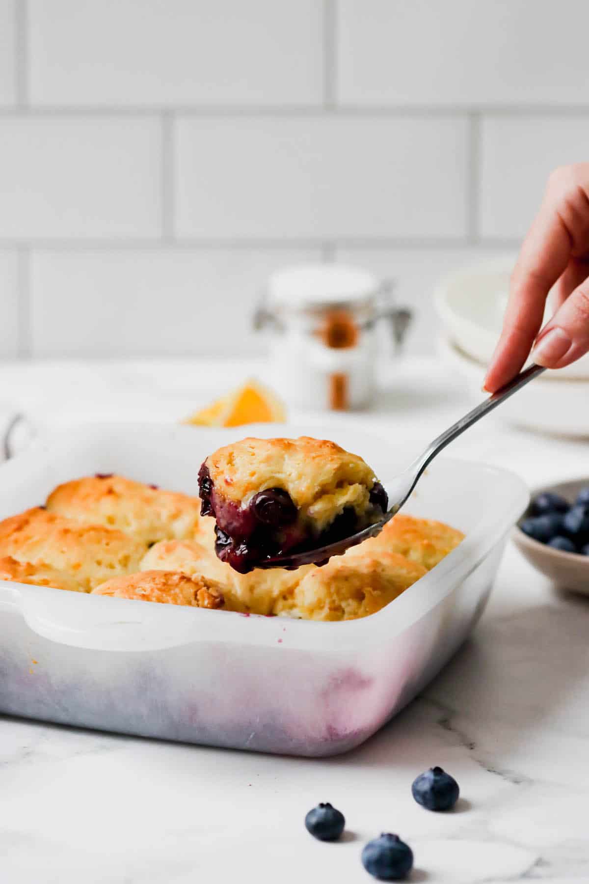 Blueberry cobbler being scoop out of the baking dish