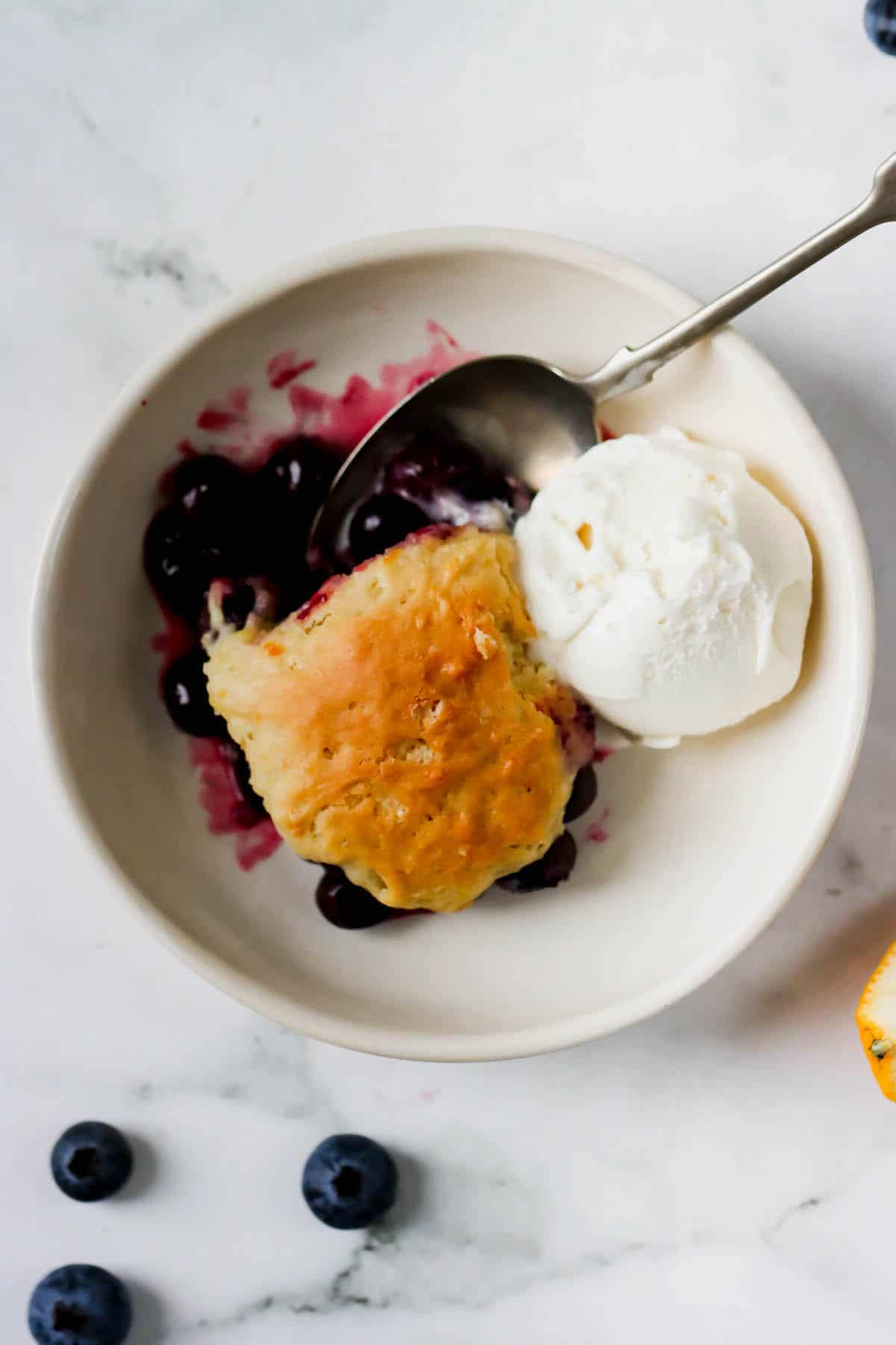 A dish of blueberry cobbler with a scoop of vanilla ice cream