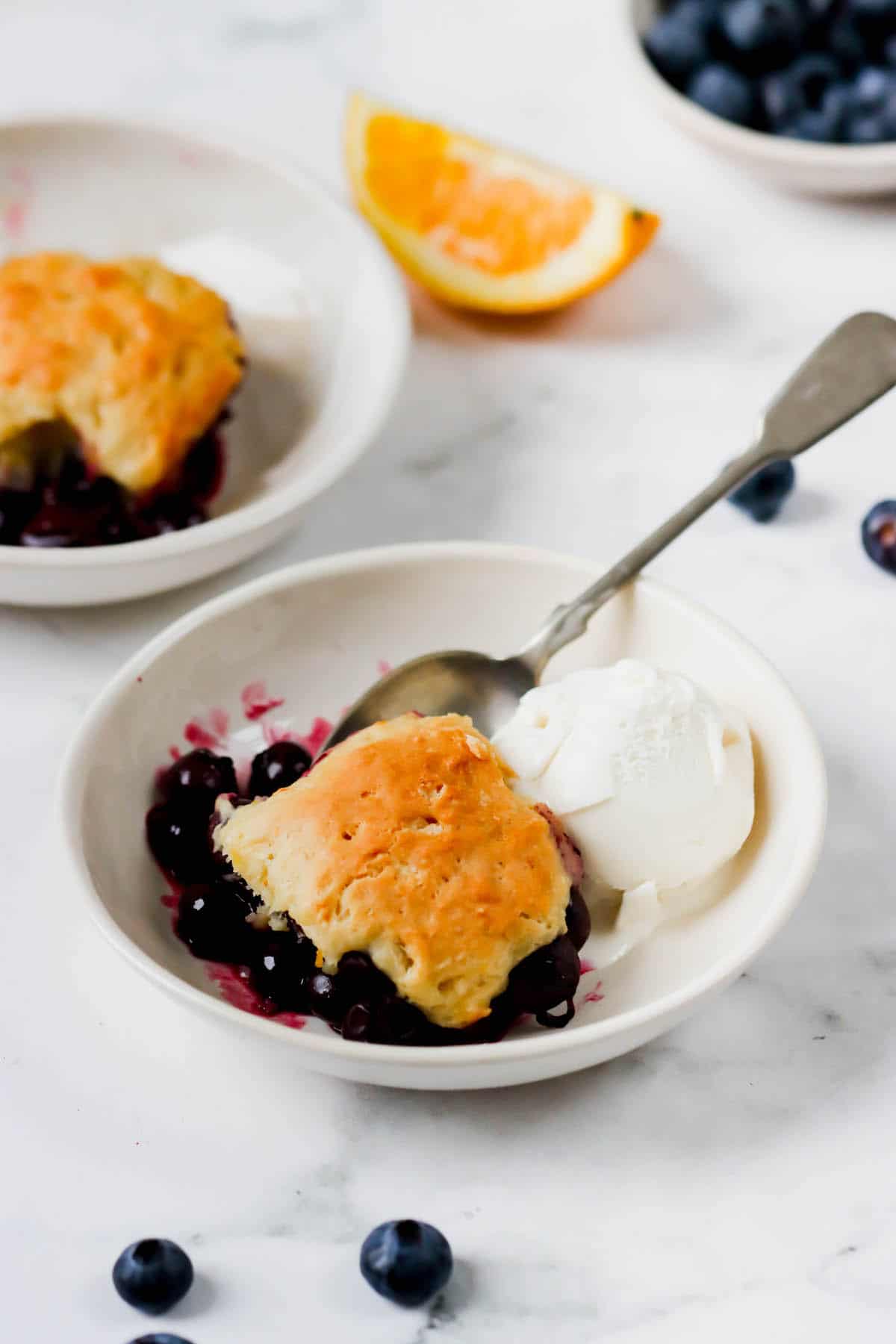 A dish of blueberry cobbler with a scoop of vanilla ice cream