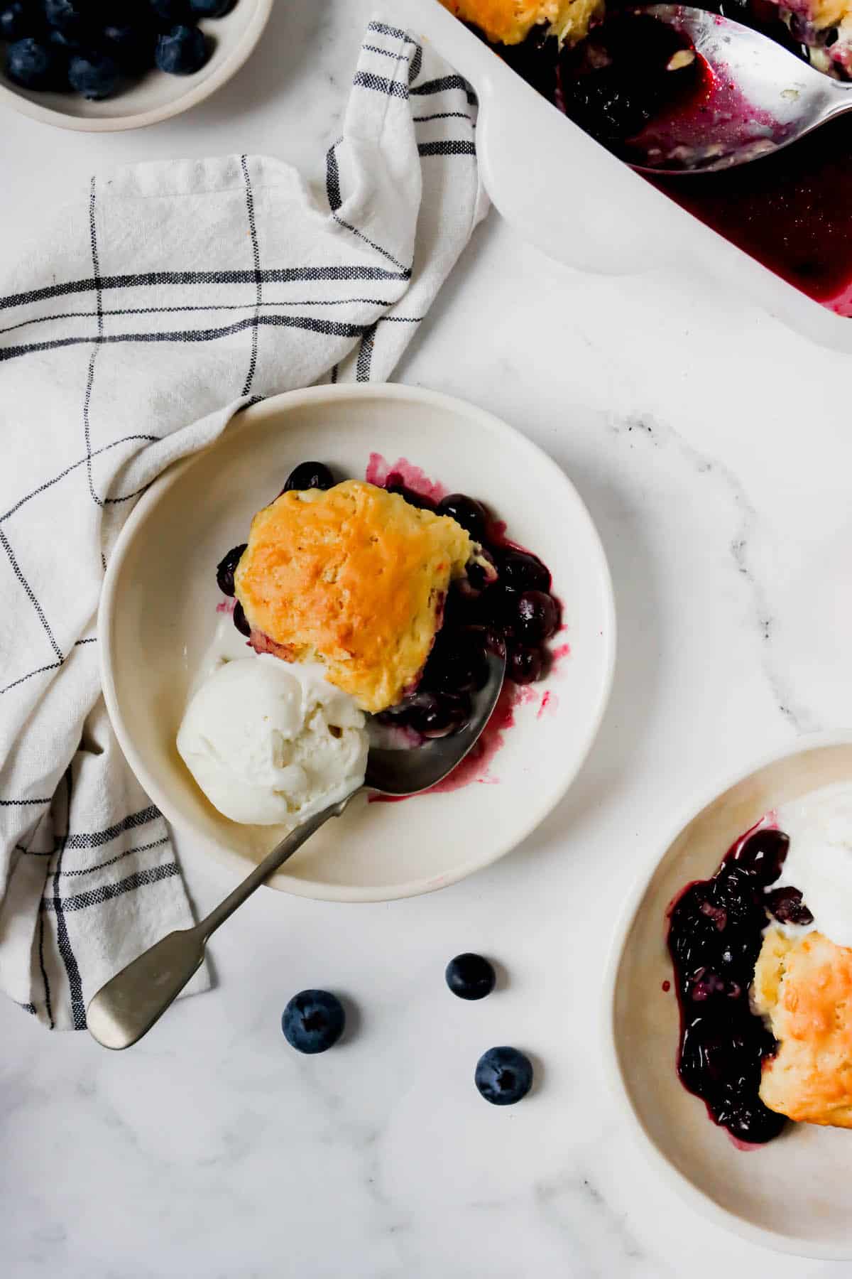 Overhead view of a plate of blueberry cobbler with ice cream