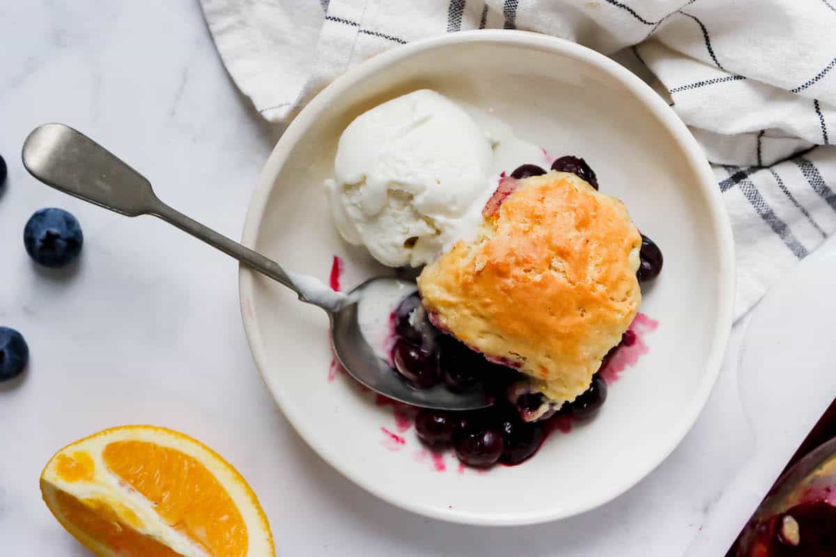 Blueberry cobbler on a plate served with a scoop of vanilla icecream