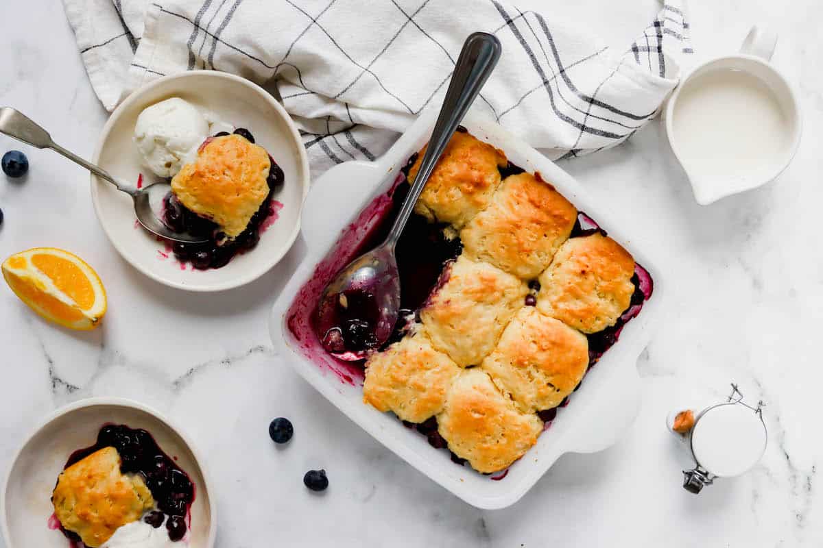 A baking dish of blueberry cobbler with three pieces missing