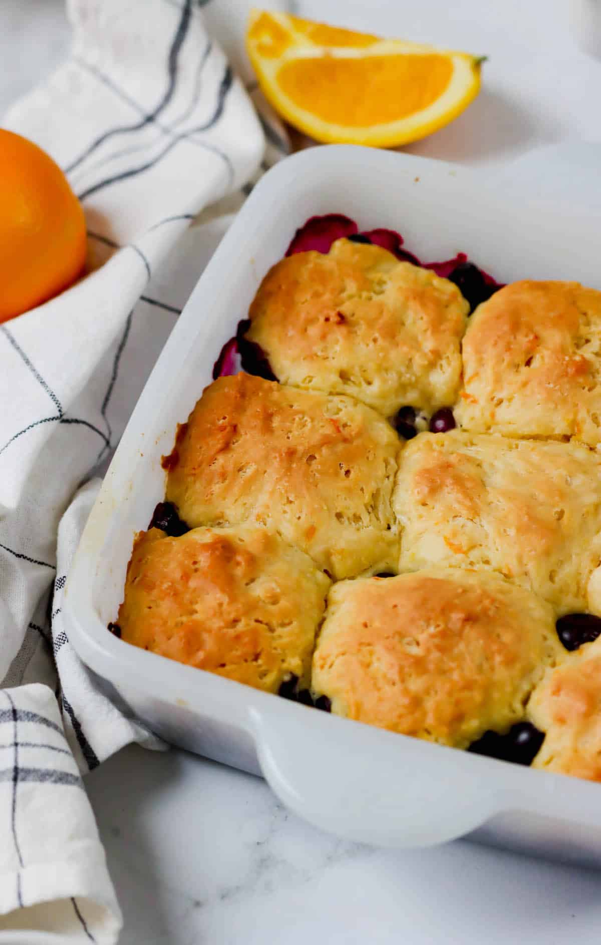 A baking dish of freshly baked blueberry cobbler with orange biscuit puffs