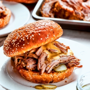 Slow cooker pulled pork sandwich with pickles and sauce.